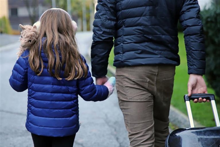 En mann og en liten jente går ned en gate og holder hverandre i hendene.