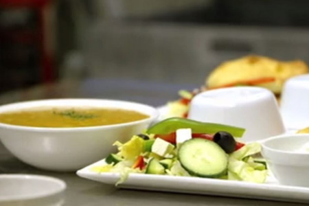 En hvit tallerken med salat ved siden av suppeskåler.