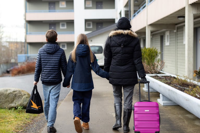 Tre personer som går langs fortauet og holder hverandre i hånden.