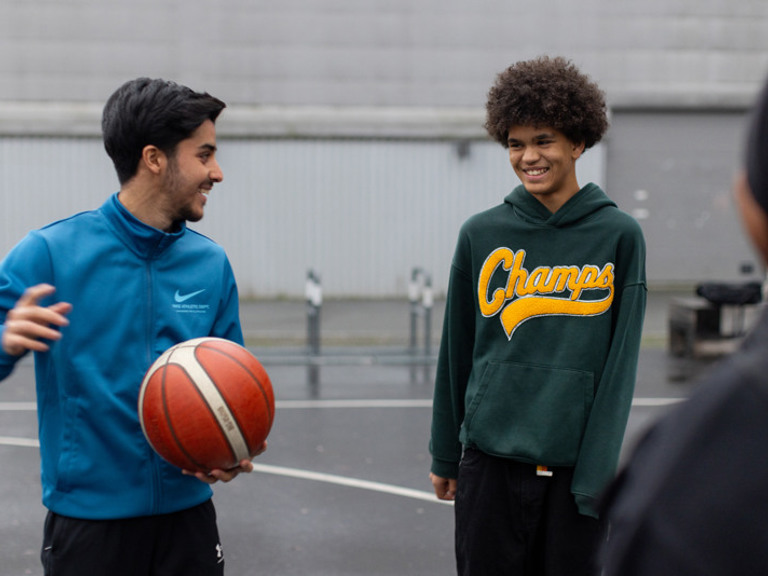 En mann som står ved siden av en annen mann og holder en basketball.