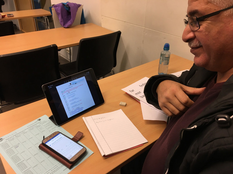 En mann sitter ved et bord med et nettbrett.