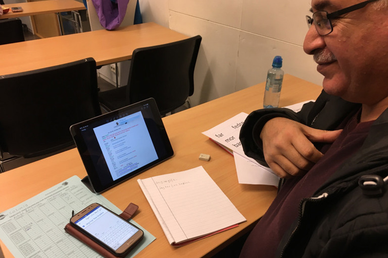 En mann sitter ved et bord med et nettbrett.