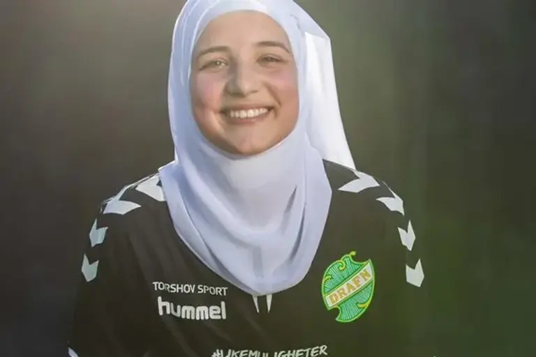 En kvinne med skaut som smiler når hun stiller opp på et bilde.