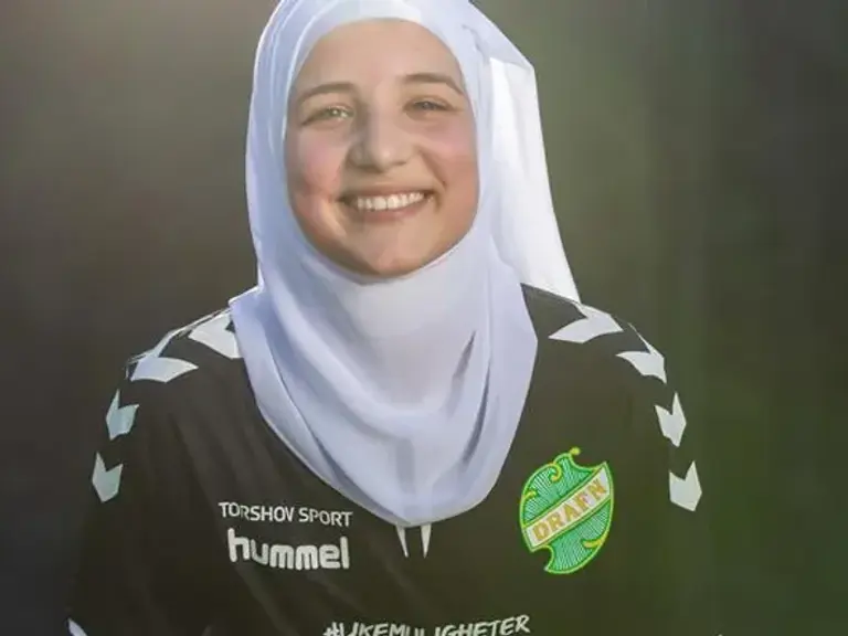 En kvinne med skaut som smiler når hun stiller opp på et bilde.