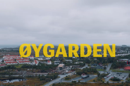 Et stort gult skilt med påskriften Oygaden på toppen av en by.