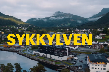 Et flyfoto av en by med fjell i bakgrunnen.