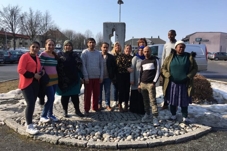 En gruppe mennesker som står foran et skilt.